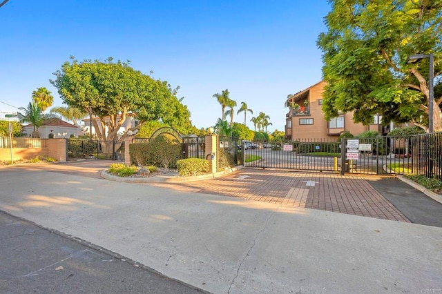 view of street with a gated entry, curbs, and a gate