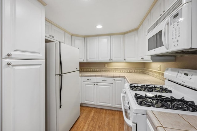 kitchen with white appliances, tile countertops, light wood-style flooring, recessed lighting, and white cabinets