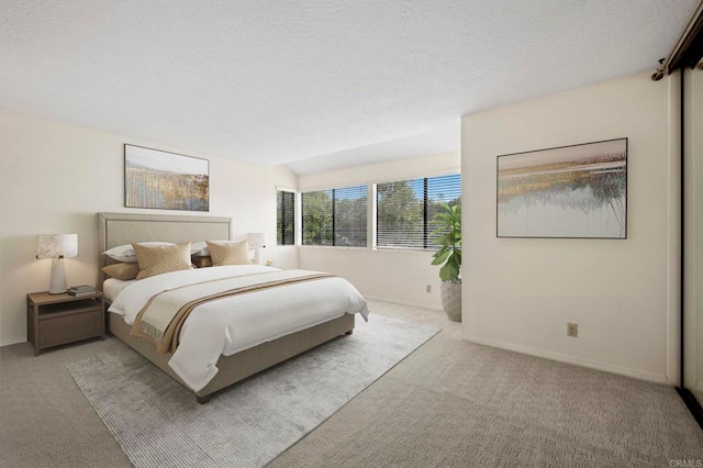 carpeted bedroom with vaulted ceiling, baseboards, and a textured ceiling