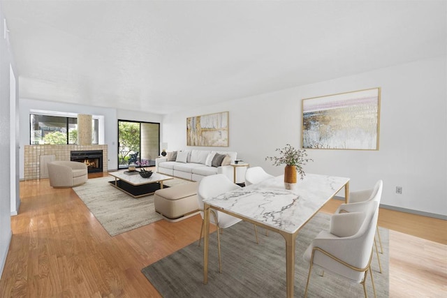 living area featuring light wood finished floors, baseboards, and a lit fireplace