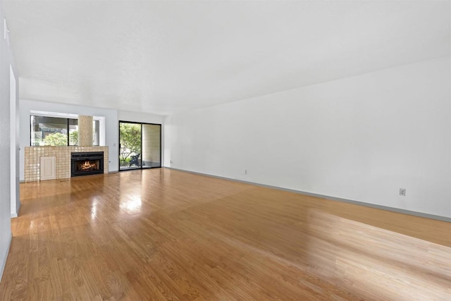 unfurnished living room featuring baseboards, a lit fireplace, and wood finished floors