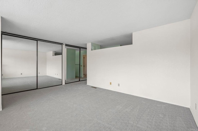 unfurnished bedroom with multiple closets, carpet floors, and a textured ceiling