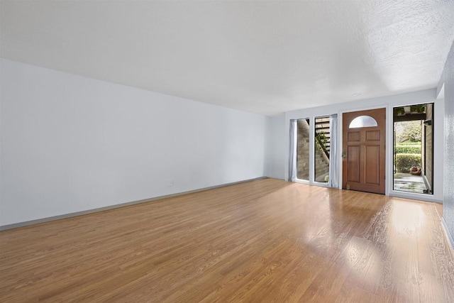 entrance foyer featuring a textured ceiling, baseboards, and wood finished floors