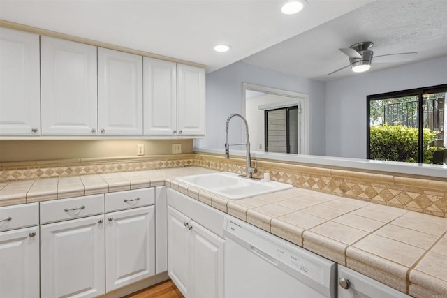 kitchen with white cabinets, white dishwasher, and a sink