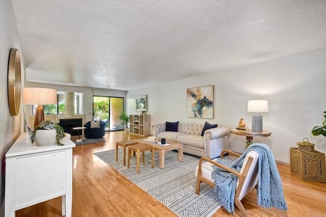 4015 Canario St Unit D, Carlsbad, CA 92008 - living room featuring light wood-type flooring, a textured ceiling, and a brick fireplace