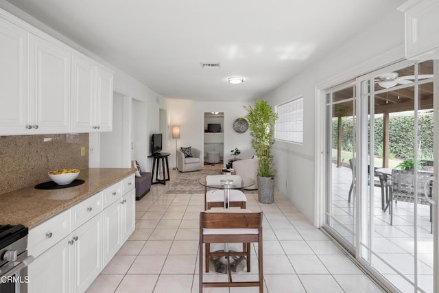 kitchen with white cabinets, light tile patterned floors, visible vents, and backsplash