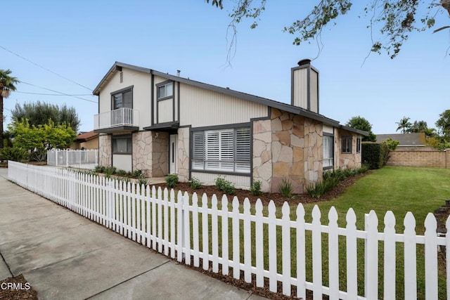 view of front of house with a fenced front yard, stone siding, a balcony, and a chimney