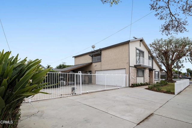 view of home's exterior featuring stucco siding, concrete driveway, a balcony, and fence