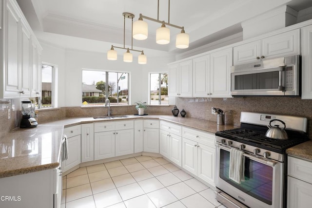 kitchen with pendant lighting, ornamental molding, appliances with stainless steel finishes, white cabinets, and a sink