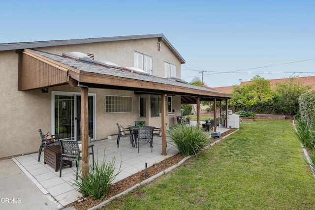 back of house with a patio area, a lawn, and stucco siding