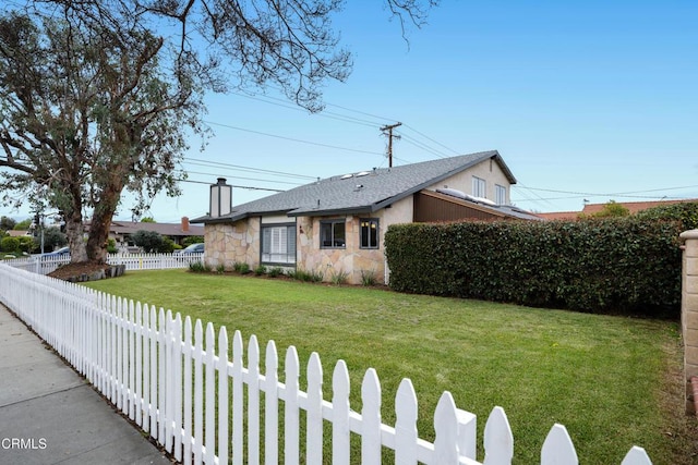 view of front of home with a chimney, stone siding, a front lawn, and a fenced backyard