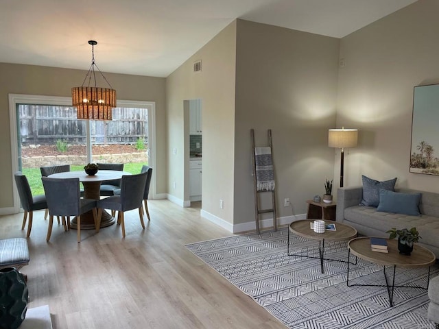 living room with visible vents, lofted ceiling, light wood finished floors, baseboards, and a chandelier