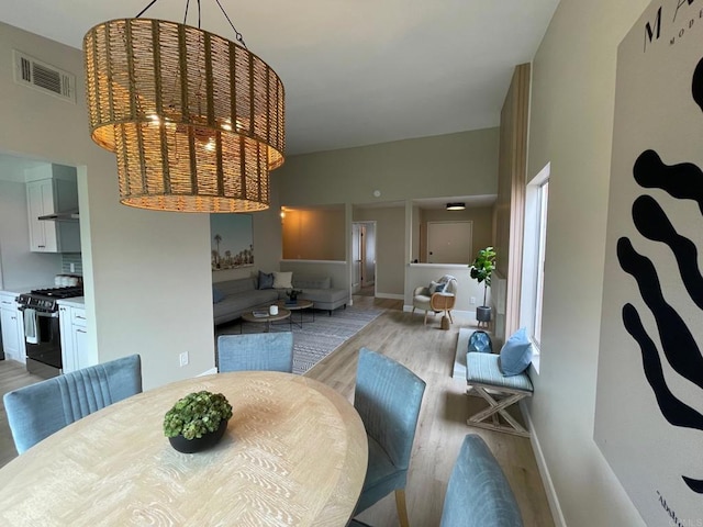 dining space with light wood-style flooring, baseboards, and visible vents