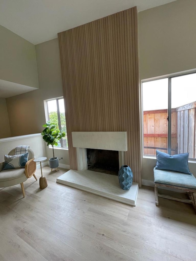 living room with a high ceiling, wood finished floors, baseboards, and a large fireplace