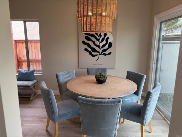 dining room with a healthy amount of sunlight, baseboards, and light wood finished floors