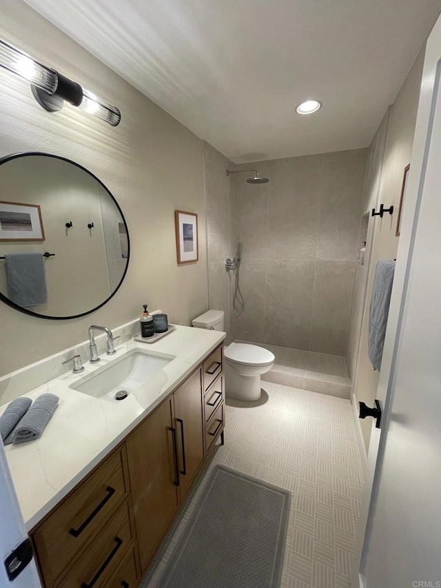 bathroom featuring vanity, toilet, and a tile shower