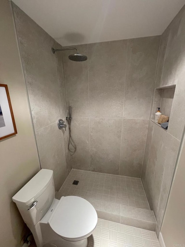 bathroom with a tile shower and toilet