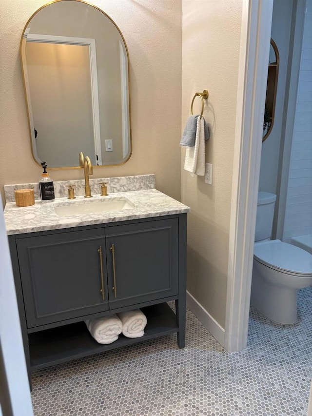 full bathroom with toilet, vanity, a shower, and baseboards