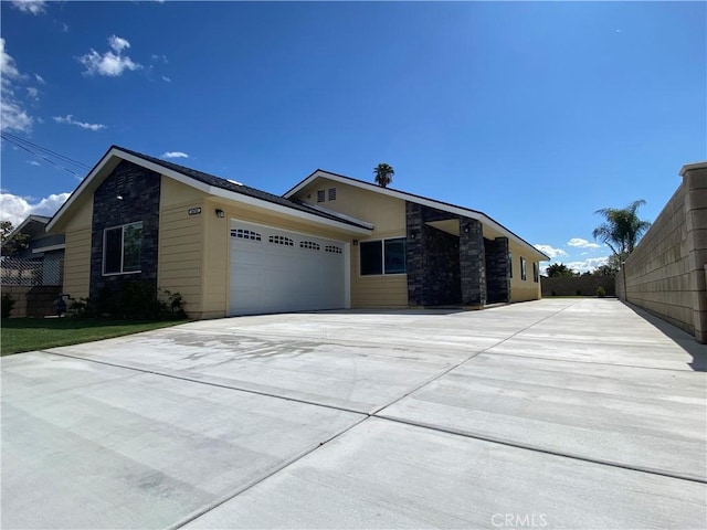 view of front facade featuring concrete driveway, an attached garage, and stone siding