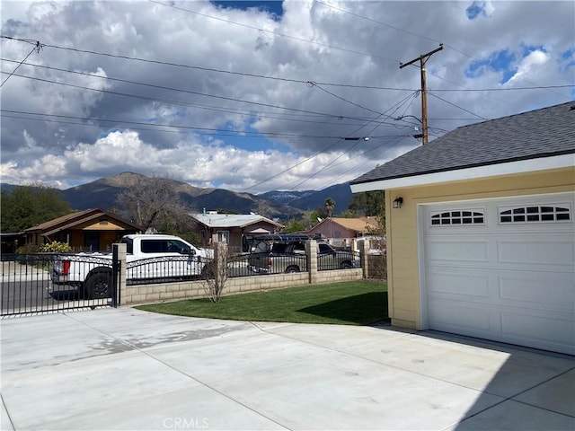 garage featuring a mountain view, concrete driveway, and fence