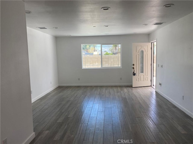 interior space featuring visible vents, dark wood-style flooring, and baseboards