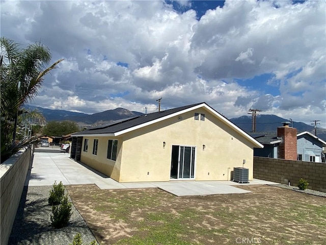 rear view of house featuring stucco siding, a mountain view, a patio, and fence