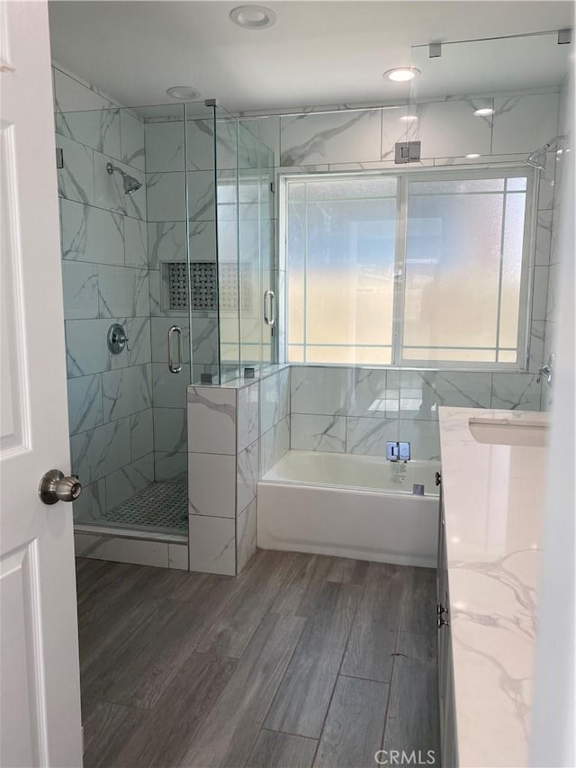 bathroom featuring a bathtub, a shower stall, and wood finished floors