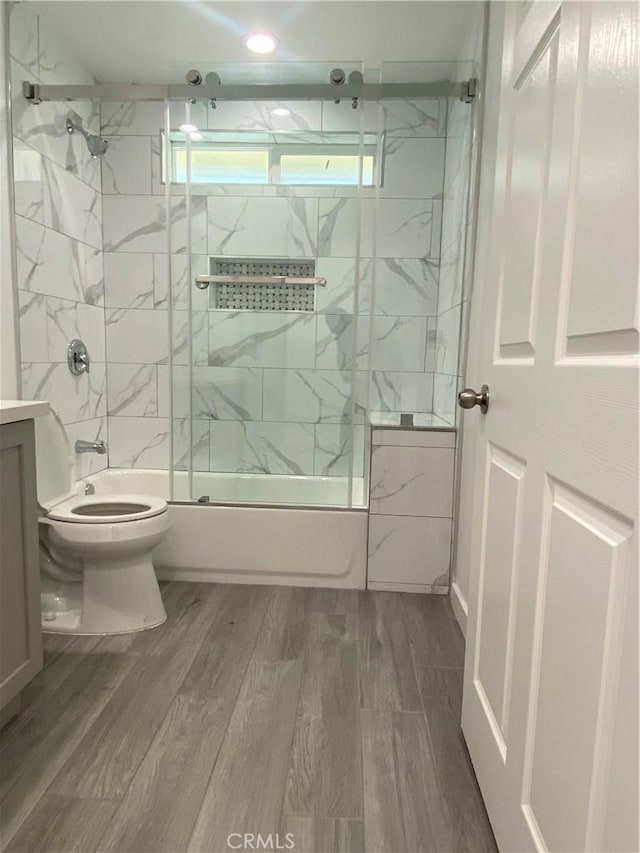 full bathroom featuring vanity, toilet, wood finished floors, and combined bath / shower with glass door