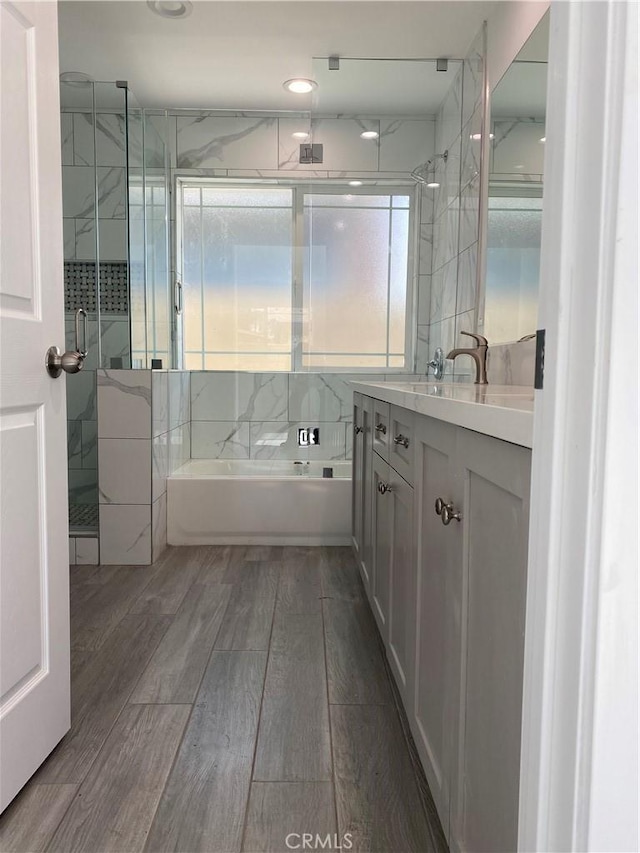 full bathroom featuring a shower with shower door, a bathing tub, wood finished floors, and vanity