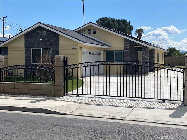 view of front of property with concrete driveway, an attached garage, stone siding, and a fenced front yard