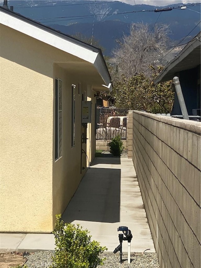 view of property exterior featuring fence, a mountain view, and stucco siding