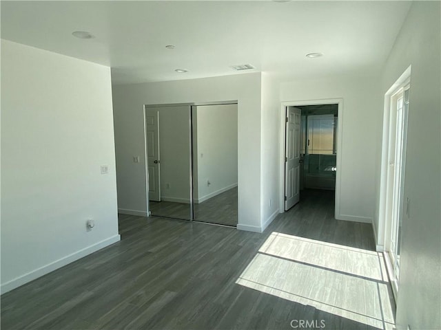 unfurnished bedroom featuring dark wood finished floors, visible vents, baseboards, and a closet