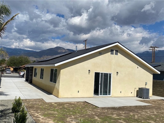 rear view of house with a patio, fence, central AC, and stucco siding