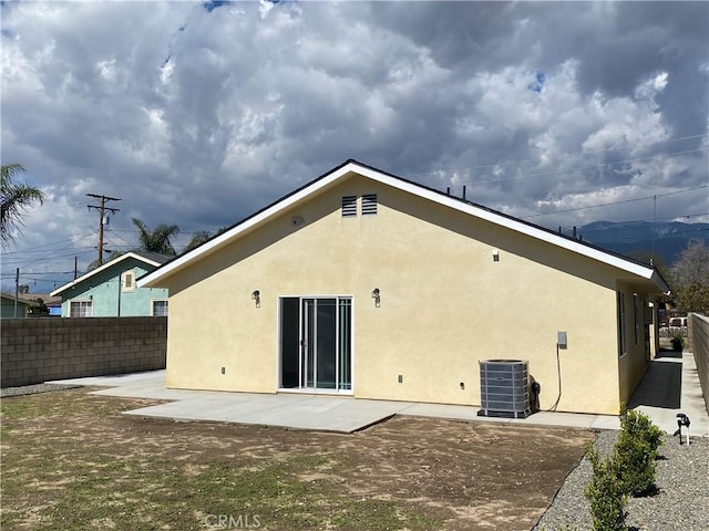 rear view of house with central air condition unit, a patio, stucco siding, and fence