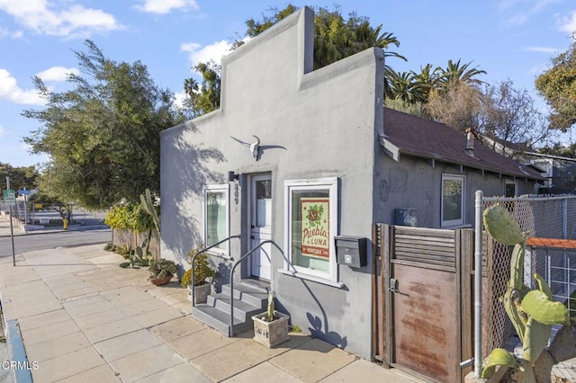 exterior space with stucco siding, fence, and a gate