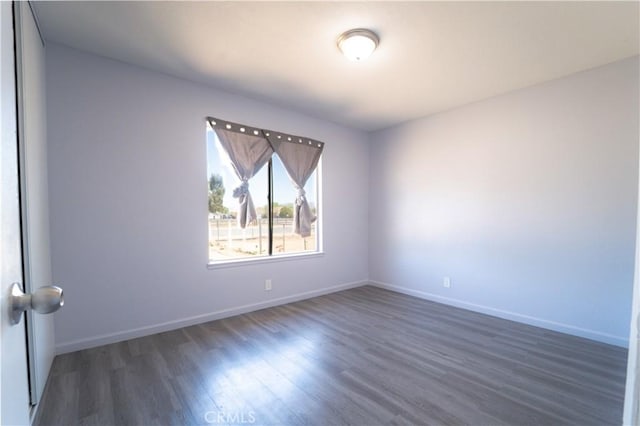 empty room featuring wood finished floors and baseboards