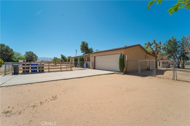 view of front facade featuring a gate, fence, concrete driveway, and a garage