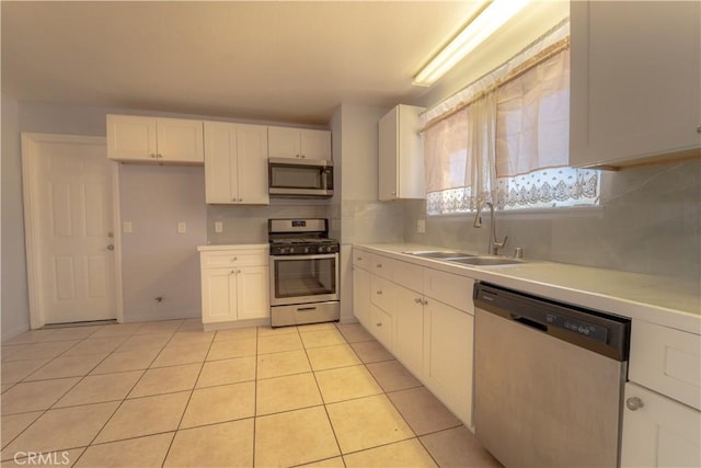 kitchen with stainless steel appliances, light countertops, a sink, decorative backsplash, and white cabinetry