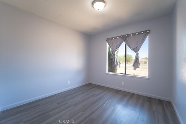 spare room featuring baseboards and wood finished floors
