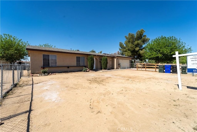 view of front of home with an attached garage, fence, and stucco siding