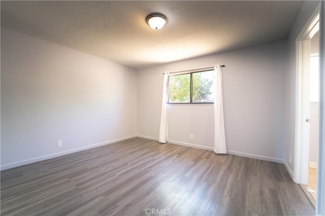spare room with baseboards and wood finished floors