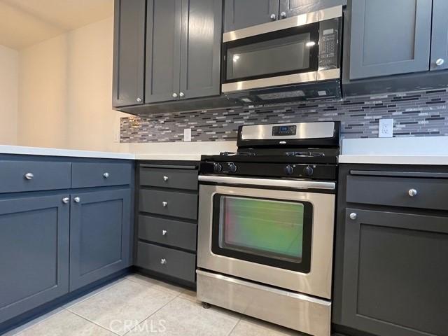 kitchen with light countertops, light tile patterned floors, backsplash, and appliances with stainless steel finishes