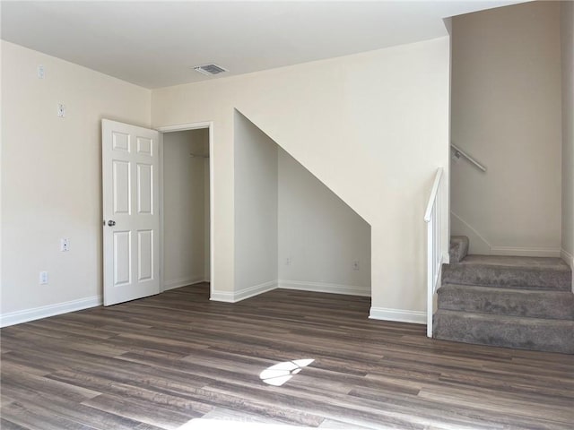 unfurnished living room with visible vents, baseboards, wood finished floors, and stairs