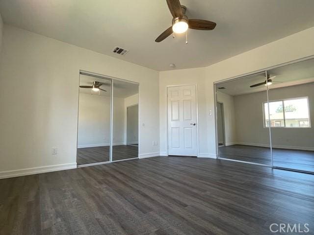 unfurnished bedroom featuring dark wood-type flooring, baseboards, visible vents, and ceiling fan