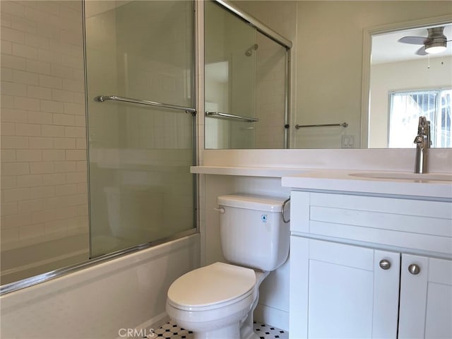 full bath with toilet, vanity, ceiling fan, and bath / shower combo with glass door