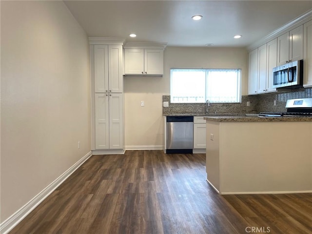 kitchen featuring a sink, backsplash, dark wood-style floors, appliances with stainless steel finishes, and baseboards