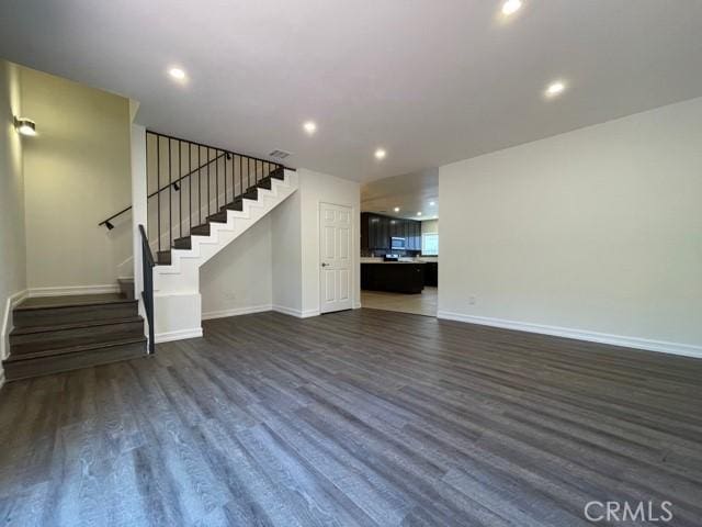 unfurnished living room with dark wood-style floors, stairway, recessed lighting, and baseboards