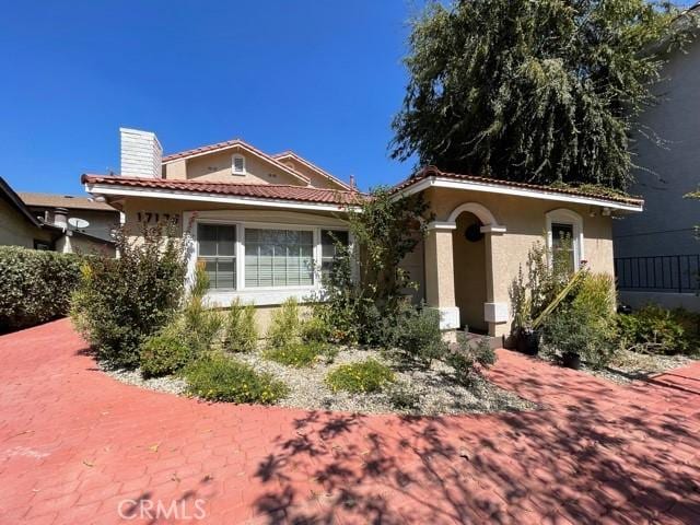 mediterranean / spanish house with stucco siding, a tiled roof, and a chimney