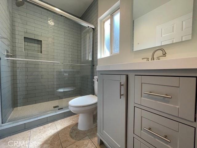 full bath with vanity, toilet, a stall shower, and tile patterned flooring