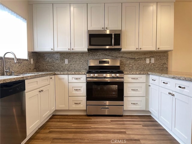 kitchen with a sink, decorative backsplash, appliances with stainless steel finishes, and wood finished floors